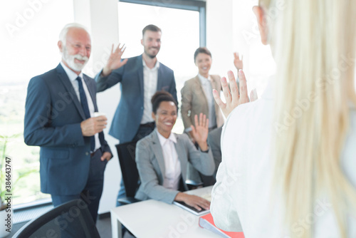 Business people waving goodbye to female colleague