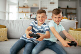 Happy brothers playing video games. Young brothers having fun while playing video games in living room..