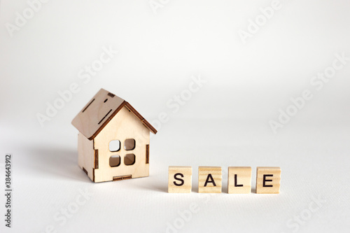 A small wooden toy house, stand on white background and woods lettering Sale