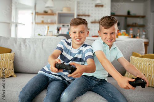 Happy brothers playing video games. Young brothers having fun while playing video games in living room..