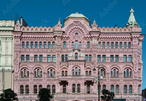 Ostrovsky Square, Saint Petersburg, Russia, 11.10.2020. Pink red historical building Bazin's House in Russian style. Decorative facade with turrets, windows, stucco. Blue sky background