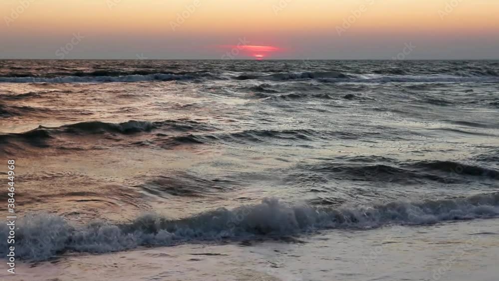 Sun goes down in sea, epic red color sky with stormy white waves on sea shore sand beach. Magic sunset vacation romantic evening Sun goes down in sea, epic red color sky with stormy white waves on sea shore sand beach. Magic sunset vacation romantic evening