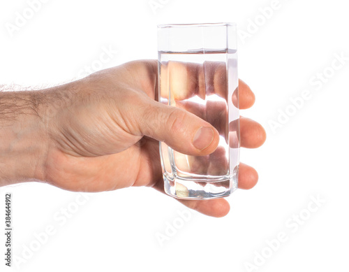 close-up of a man's hand holding a transparent glass with crystal clear water, on a white background.
