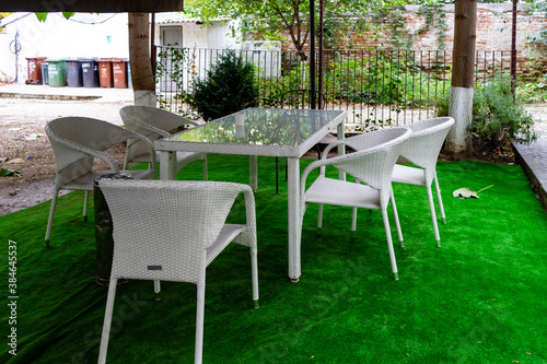 Patio garden terrace table and six chairs on an artificial green grass carpet. © sorin