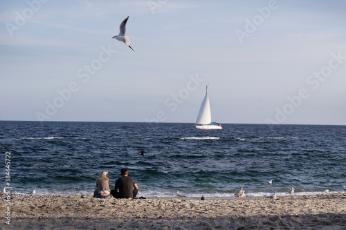 couple on sea beach with blue water horizon boat and fly seagull bird photo