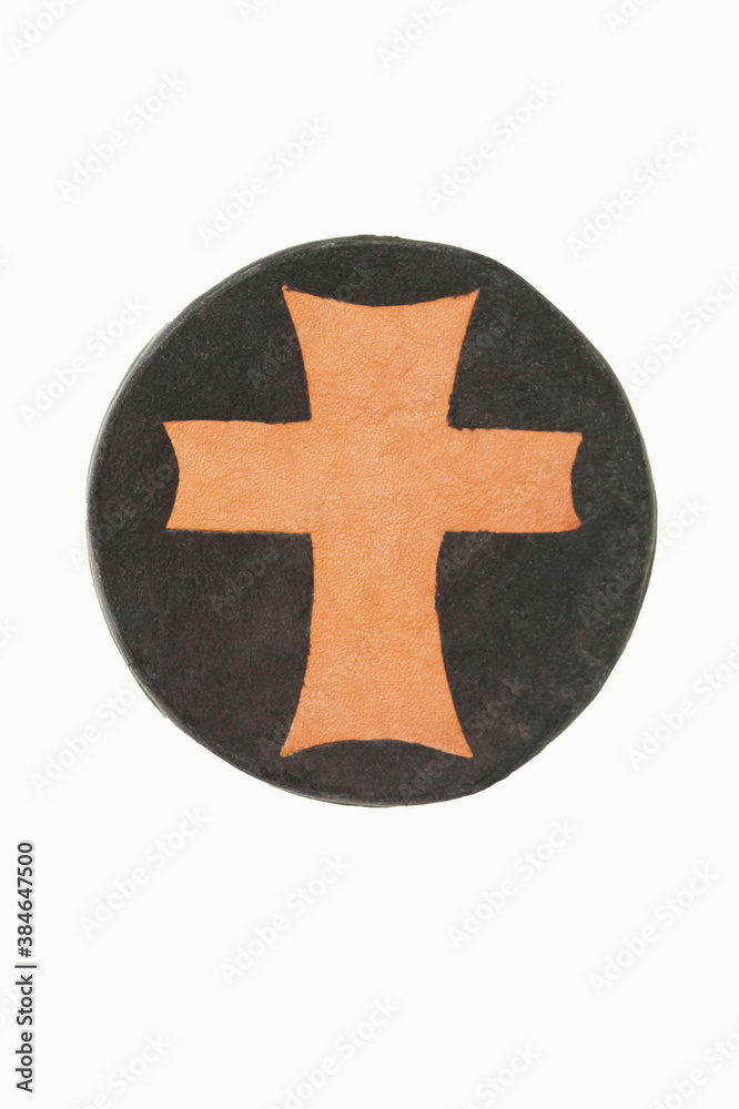 Obraz premium Tan leather medallion cross on a circular rawhide background isolated. The cross is handmade in two tones of leather and the cross symbolizes Christ in the world.