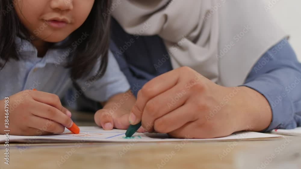 Asian muslim mother drawing with her daughter, single mom teaching baby girl, learning on the floor, happy family