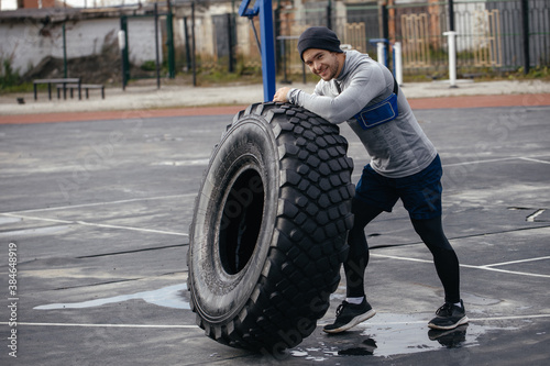 sporty white athletic man lifts a large tire