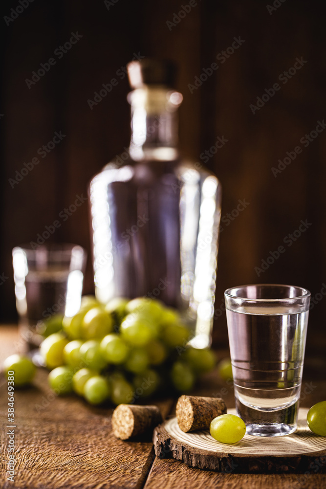 Glass of brandy based on grapes, called bagaceira in Portugal and in Italy Grappa or Graspa, with oak barrel in the background Glass of brandy based on grapes, called bagaceira in Portugal and in Italy Grappa or Graspa, with oak barrel in the background