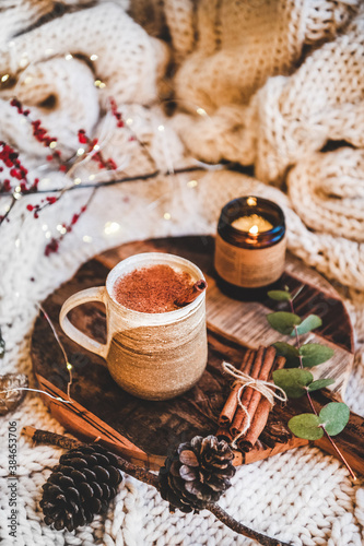 Turkish traditional wintertime hot drink Salep. Mug of sweet warming Salep drink with ground cinnamon on tray over knitted blanket. Turkish seasonal cuisine, Christmas and New Year mood photo