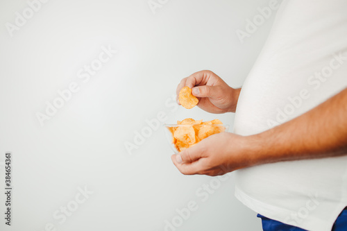 overweight man eating fattening potato chips