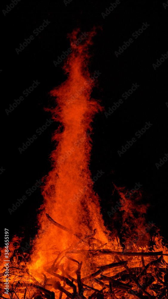 VERTICAL: Beautiful shot of massive campfire rising into dark summer night sky