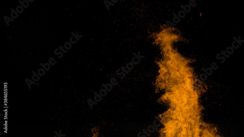 CLOSE UP: A large blaze bursts high into the dark night sky near a wildfire.