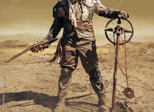 Photo of a post apocalyptic raider warrior in leather jacket with metal armor and shotgun weapon standing in wasteland with skull cross sign.