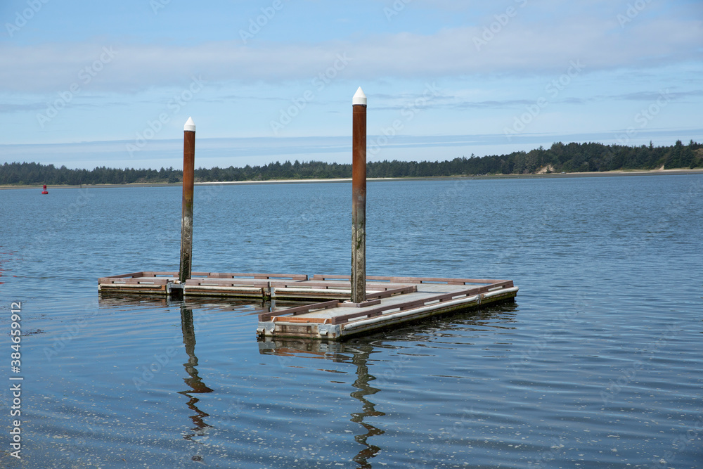 Small L shaped floating boat dock with two columns topped by white caps