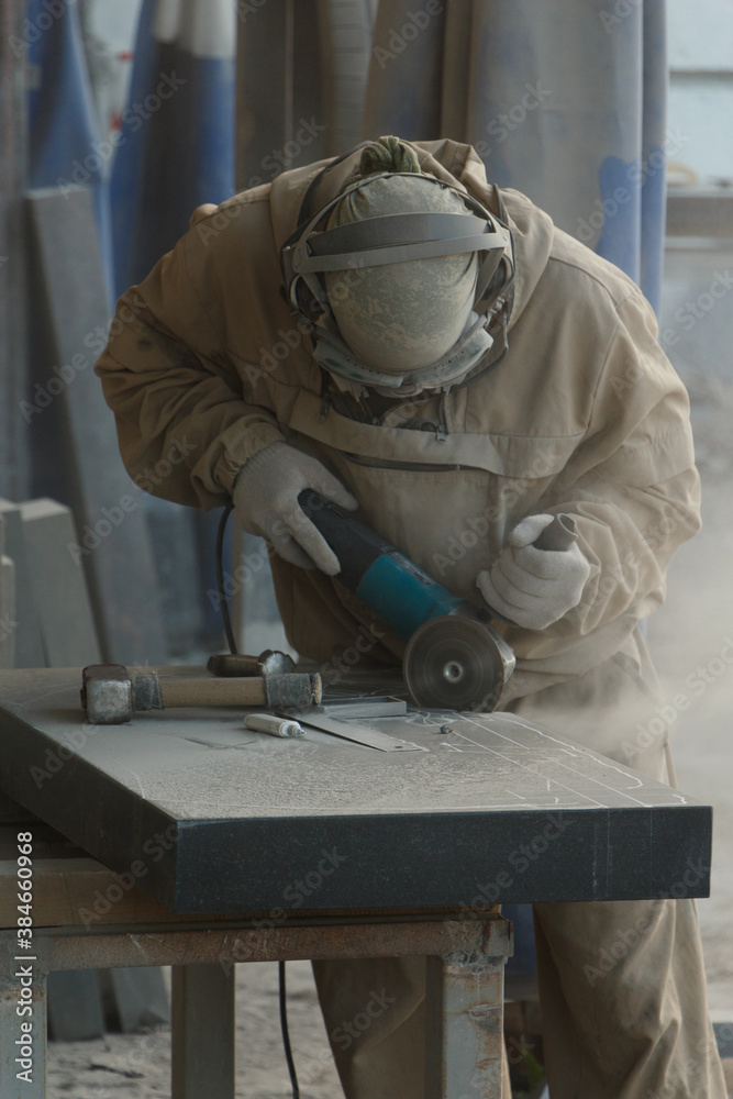 Dusty cutting of black granite by a workshop worker. Dusty cutting of black granite by a workshop worker.
