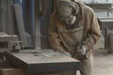 Worker wearing eye and breathing protection makes dusty processing of granite.