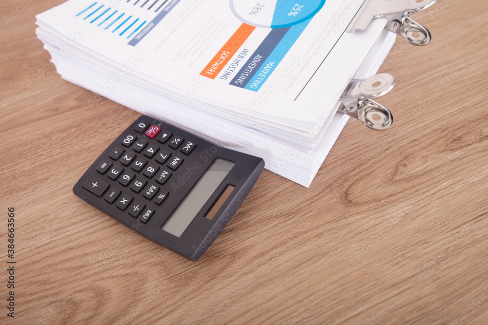 A stack of paper business documents and a calculator on the table A stack of paper business documents and a calculator on the table