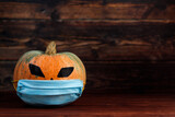 The holiday pumpkin wears  protective face mask. Halloween 2020 and coronavirus concept.