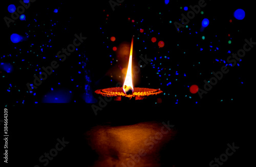 Clay diya candle illuminated in Dipavali, Hindu festival of lights. Traditional oil lamp on dark background photo