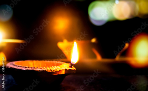 Clay diya candle illuminated in Dipavali, Hindu festival of lights. Traditional oil lamp on dark background