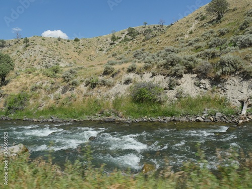 Close up of the Yellowstone River flowing along the road and right next to a rocky mountain toward Gardiner, Montana.