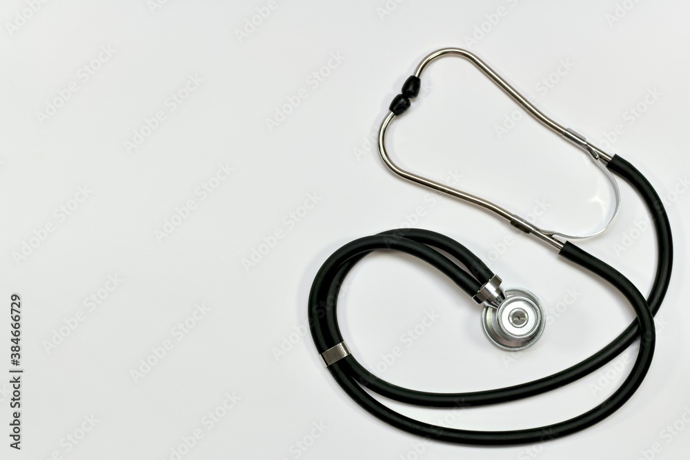 A medical stethoscope with a black hose, a membrane and headphone pads. On the bright background on the whole one. A medical stethoscope with a black hose, a membrane and headphone pads. On the bright background on the whole one.