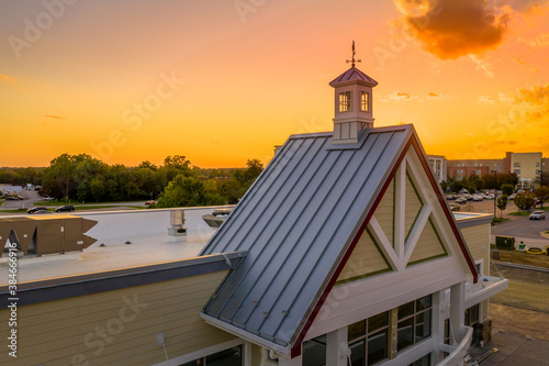 Obraz na plátně Weather vane cupola on a gable roof with colorful sunset sky