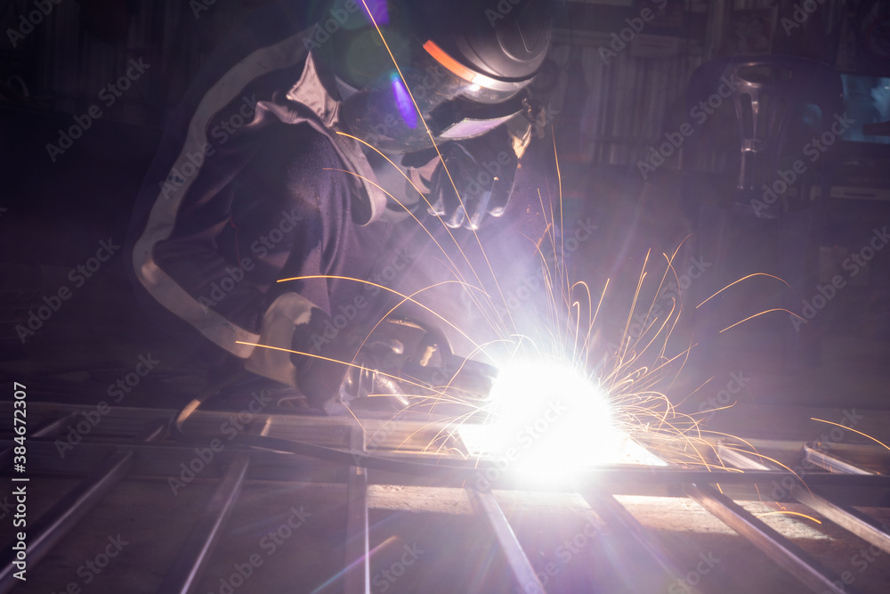 The welder is welding the parts of the iron door. The person working on a welder using an electric welding machine. The welder is welding the parts of the iron door. The person working on a welder using an electric welding machine.