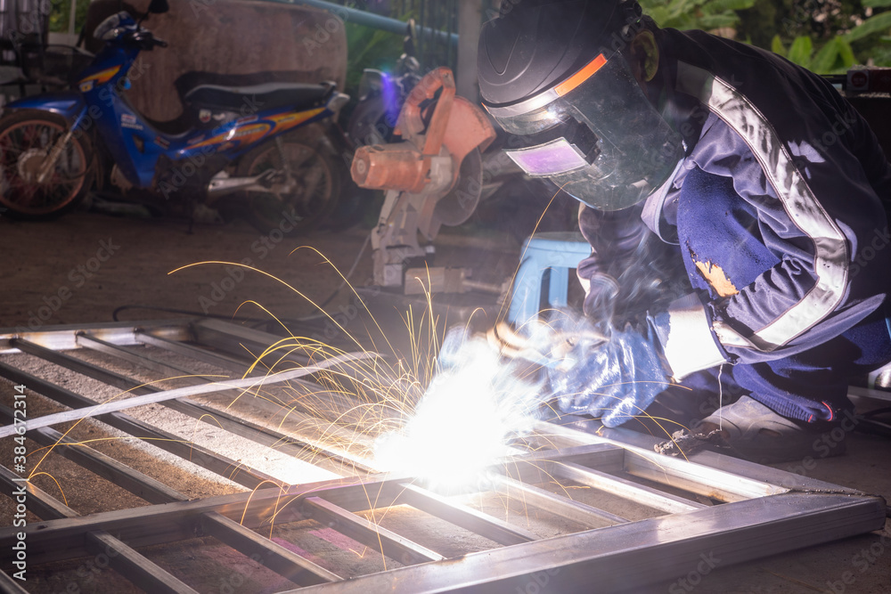 The welder is welding the parts of the iron door. The person working on a welder using an electric welding machine. The welder is welding the parts of the iron door. The person working on a welder using an electric welding machine.
