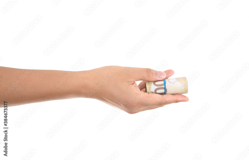 A hand holding a Canadian dollar bill in front of a white background makes a gesture of giving A hand holding a Canadian dollar bill in front of a white background makes a gesture of giving