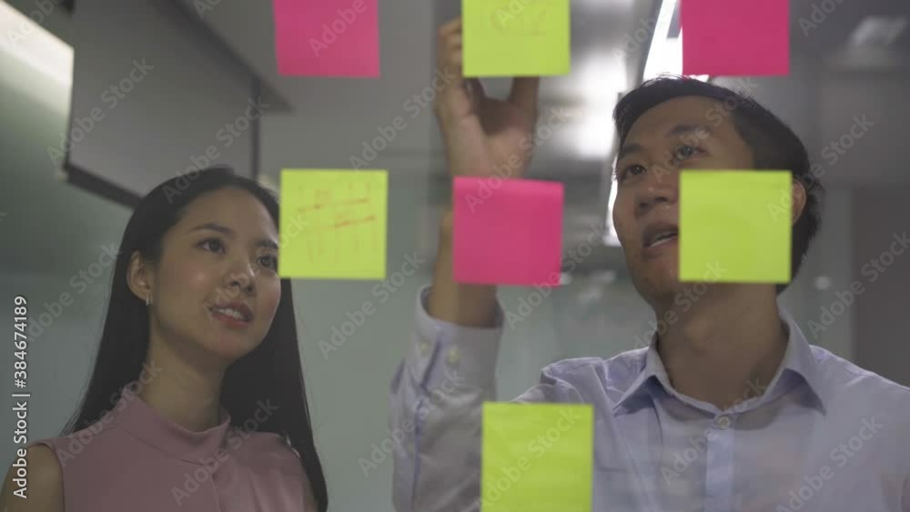 Two business coworkers sticking post it notes on glass, planning, strategy, organization - 4K High Quality Footage Two business coworkers sticking post it notes on glass, planning, strategy, organization - 4K High Quality Footage