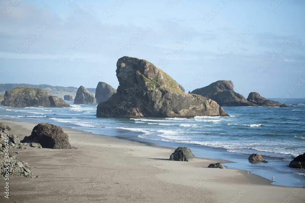 Rolling waves crashing in past rock stacks on an Oregon beach
