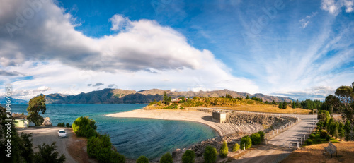 Lake Hawea Village Panorama on a beautiful day at golden hour - view from the Lake Hawea Dam in Mount Aspiring National Park, Otago Region, New Zealand, Southern Alps.
