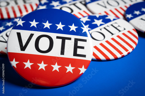 A group of red, white and blue VOTE button on a blue background