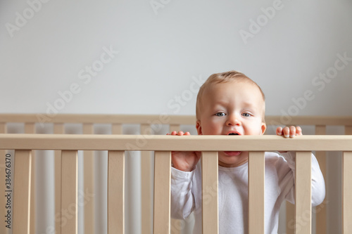 Tableau sur toile Blond cute little baby biting wooden bed headboard