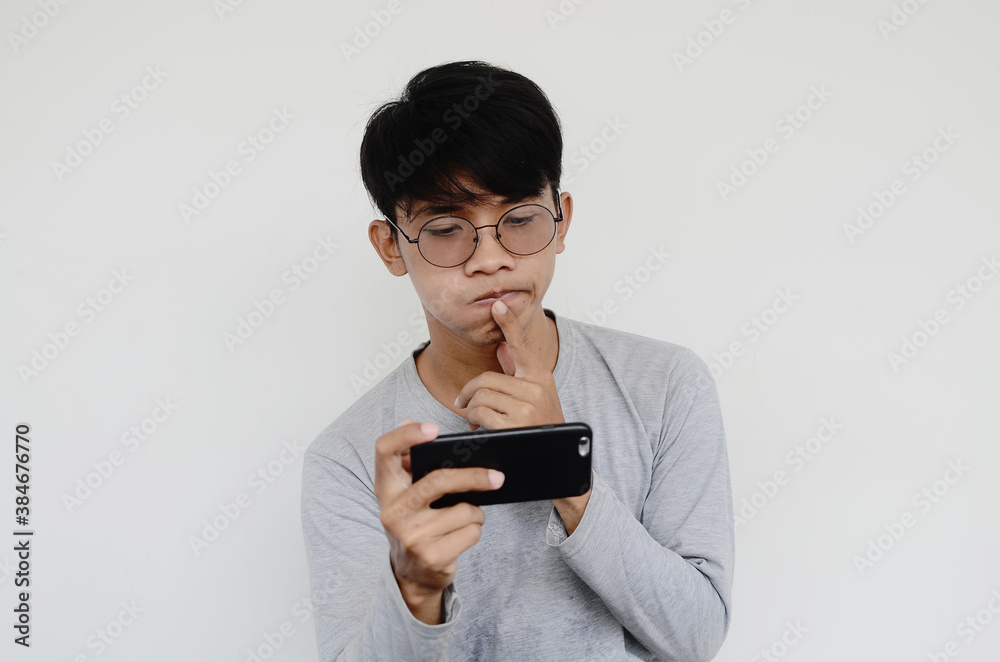 Portrait of a confused asian man looking at a smartphone Portrait of a confused asian man looking at a smartphone