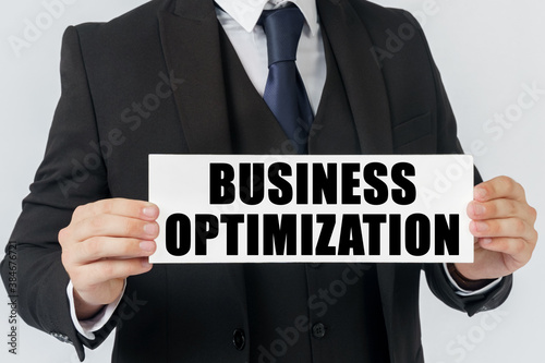 A businessman holds a sign in his hands which says - BUSINESS OPTIMIZATION