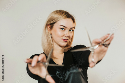 close-up portrait of a female hairdresser of European appearance. Hands are extended in front of you. Scissors in hand. Light hair color.