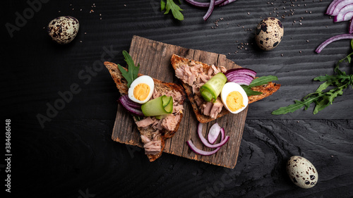 Tuna salad sandwiches on chopping board. bruschetta toast with wholemeal bread, canned tuna fish, quail eggs and onions, cucumber