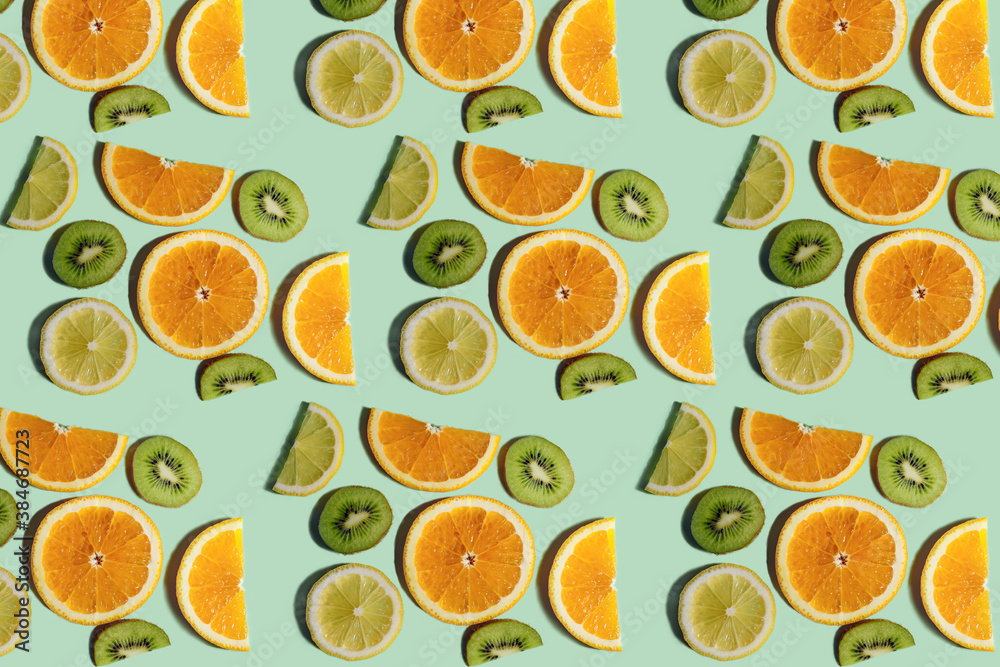 Fruit pattern. Repeating slices of kiwi, lemon and orange on a light green background. Bright fruit pattern made from natural fruits. Horizontal. The concept of healthy food and vegetarianism. Fruit pattern. Repeating slices of kiwi, lemon and orange on a light green background. Bright fruit pattern made from natural fruits. Horizontal. The concept of healthy food and vegetarianism.