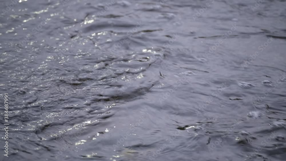 Flowing water in a shallow stream. Water surface with unwanted waves. Abstraction.