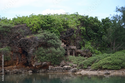 Clear waters of Inarajan Bay with a rocky cliff and green vegetation on Guam