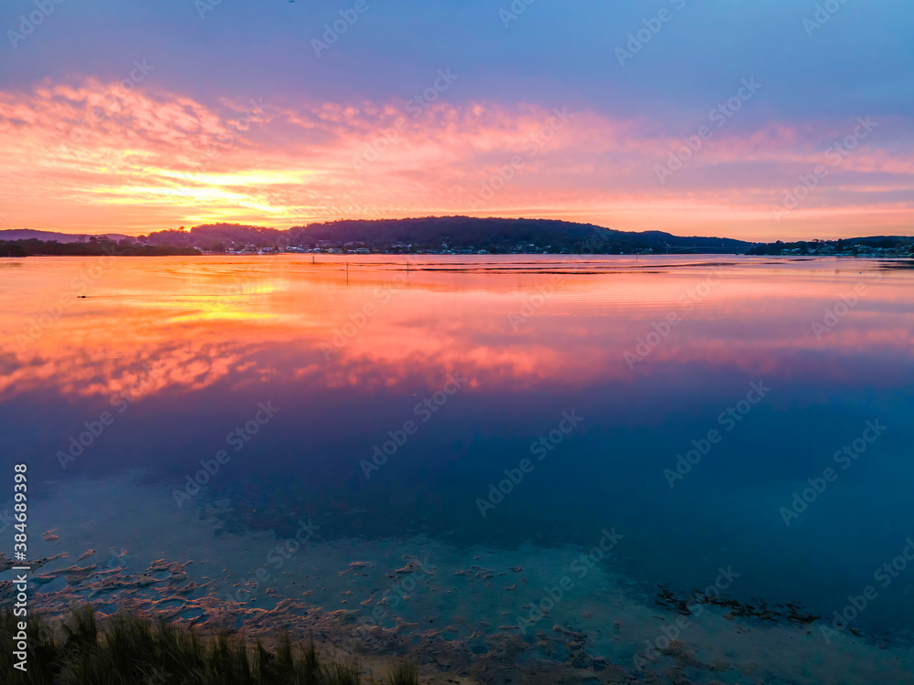 Soft high cloud, reflections and sunrise over the bay