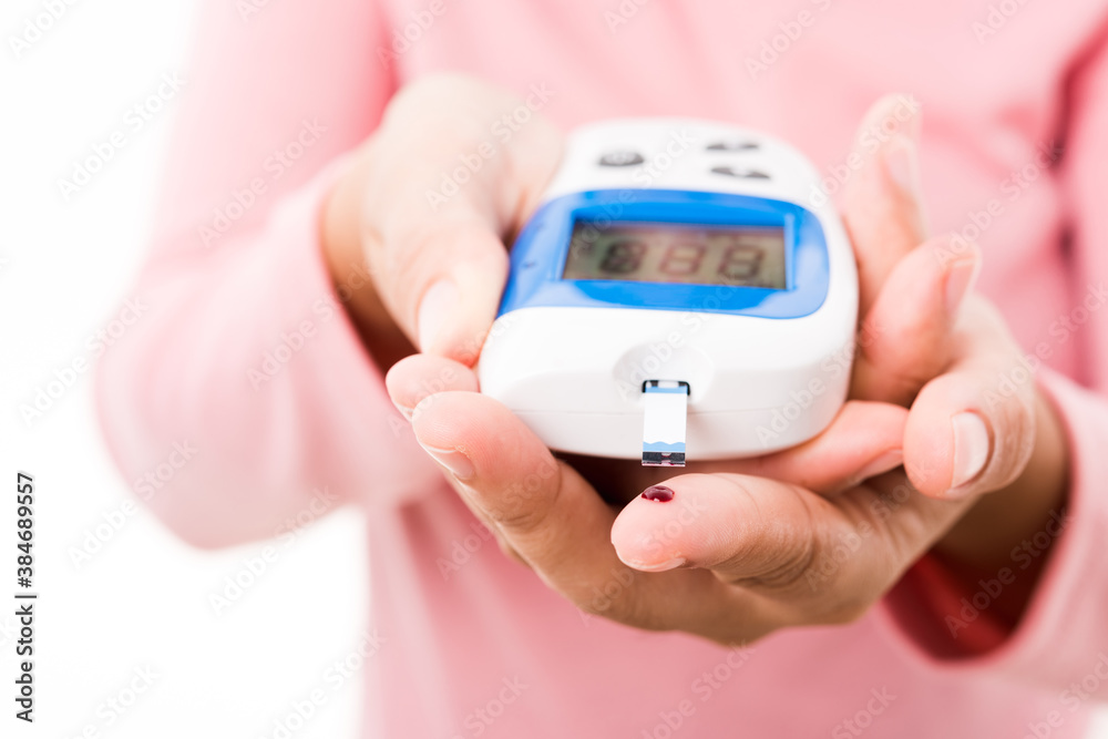Closeup hands woman measur glucose test level check with blood on finger by glucometer she monitor and control high blood sugar diabetes and glycemic health care concept isolated on white background Closeup hands woman measur glucose test level check with blood on finger by glucometer she monitor and control high blood sugar diabetes and glycemic health care concept isolated on white background