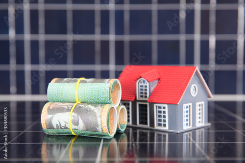 Australian dollar bills and house model on solar panel background photo