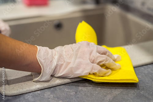 female hand in gloves cleaning kitchen sink close-up