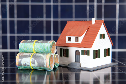 Australian dollar bills and house model on solar panel background photo