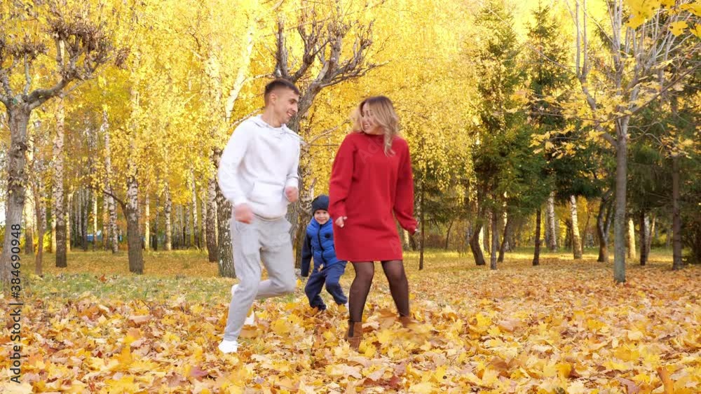 Playful family spending time in autumn city park on warm day. Father and funny little son running around mother Playful family spending time in autumn city park on warm day. Father and funny little son running around mother
