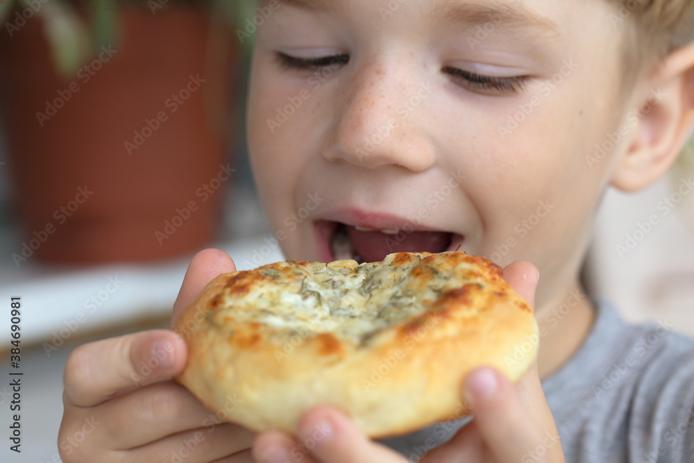 Little boy eating cheese bun in cafe outdoors Little boy eating cheese bun in cafe outdoors